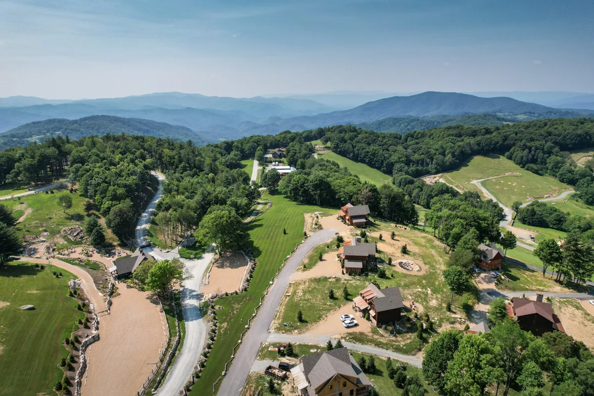 A tranquil exterior shot showcasing mountain views, scenic wooded roads, and neighboring cabins. The image captures the broader setting of the resort, inviting families to explore hiking, biking, and nature walks just beyond the doorstep.